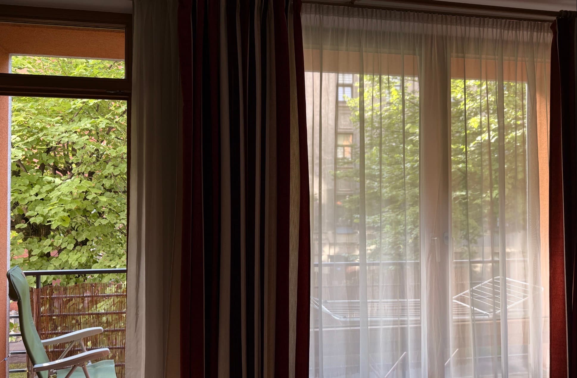Living room window view with balcony and mature green trees
